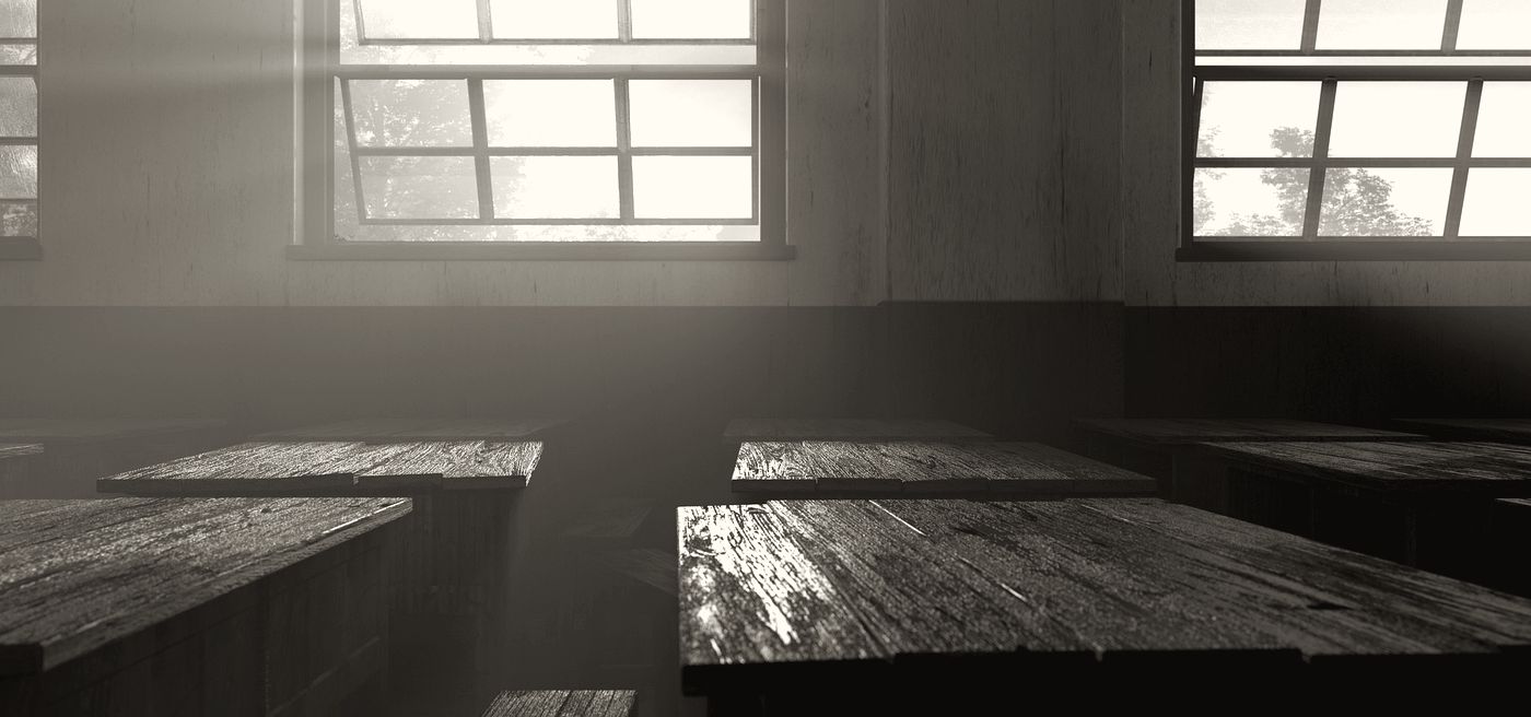 Morning light through classroom windows onto rows of wooden desks