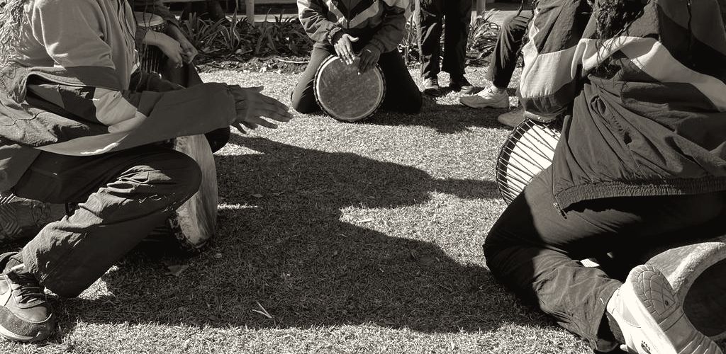 Learners in a drumming circle on a school lawn